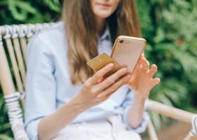 A Woman Using Her Smartphone while Holding a Credit Card